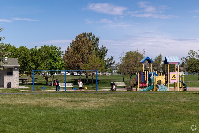 A large green lawn, trees and playground at East Park in West Point.