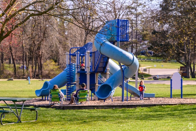 A family enjoys a sunny day at the playground in Grand Woods Park in Delta Township.