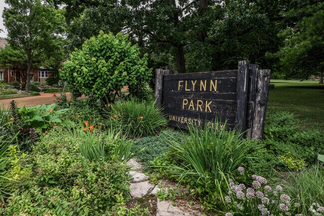 The Flynn Park signage is tucked amongst lush plants in University City.