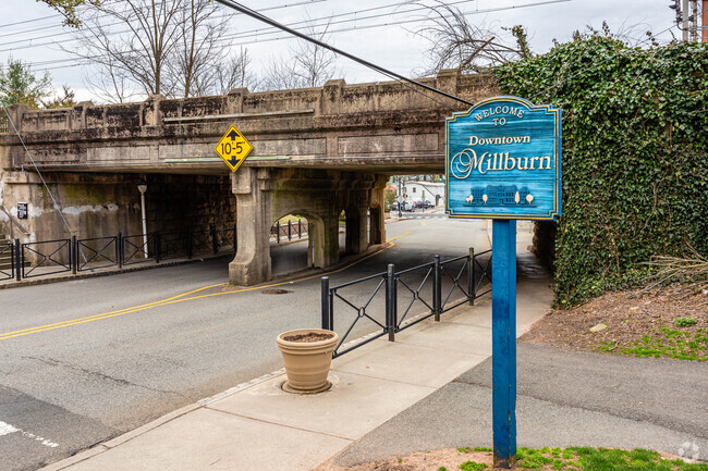 Millburn's welcome signage near a train trestle in the heart of downtown Millburn.