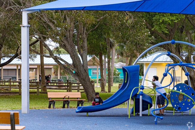 A man and his son are enjoying the playground at Gaines Park in Roosevelt Estates.