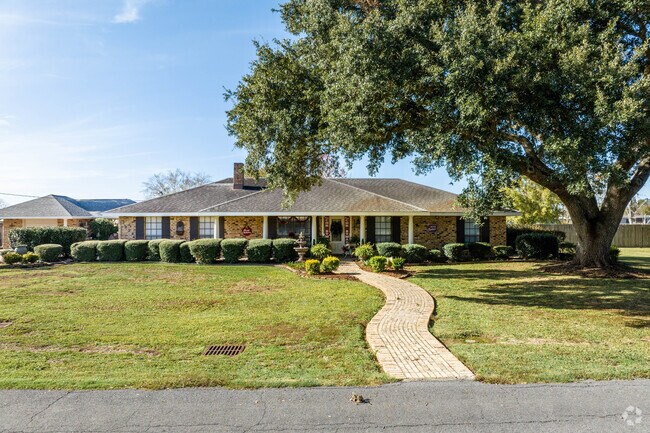 A single-story ranch-style home sits under a mature oak tree in St Martinville.