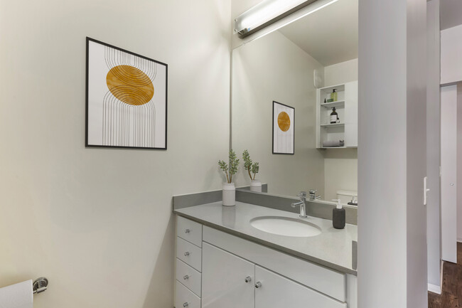 Renovated Package I bath with dark quartz countertops, white cabinetry, and hard surface flooring