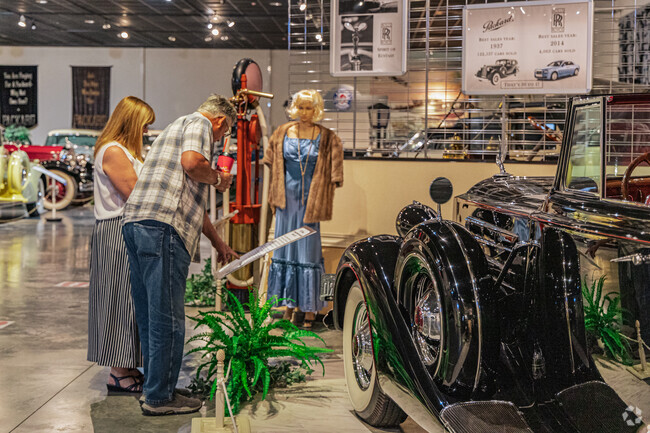 A museum guest reads the description in front of a classic car.