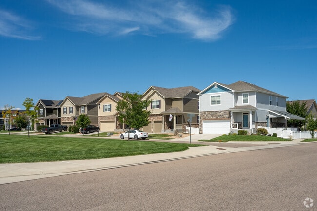 A row of modern multi level homes sit across the neighborhood green space.
