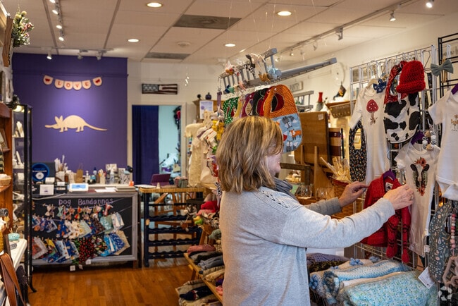 Sandy, at Chatham's The Purple Aardvark curated gift shop, perfects a display of baby clothes.