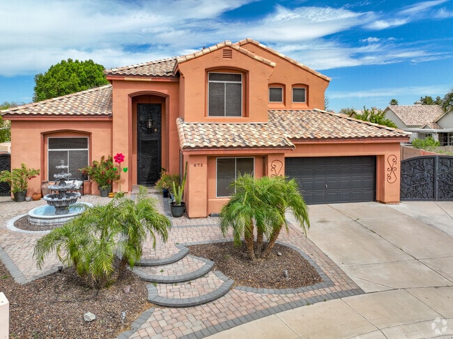 Beautiful tangerine Spanish style home with miniature palm trees adorning the front lawn.