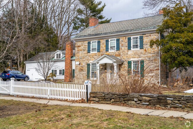 A stone home near the Bennington Monument has a plaque on it remembering its historical significance.