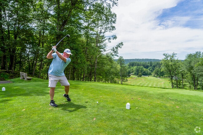 A golfer tees off at Thomas Memorial Golf Course, enjoying stunning views of Turners Falls.