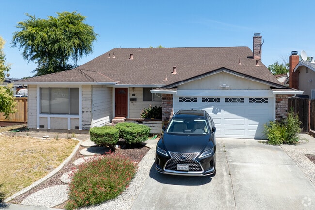 This Shawnee ranch-style home features a brick chimney, wide roofline, and curved gravel walkway.