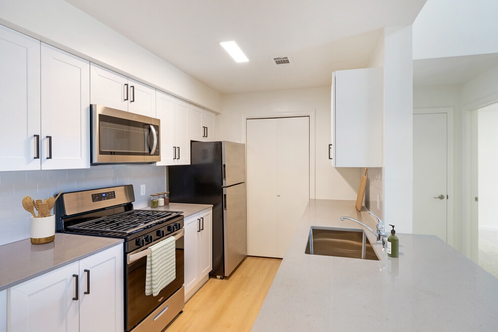 New Apartments kitchen with new stainless steel appliances, grey quartz countertops, grey subway tile backsplash, and hard surface flooring