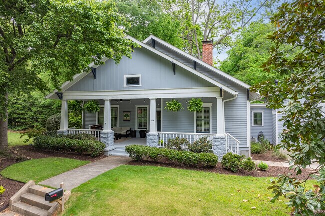 This charming Craftsman bungalow in Oakhurst features a classic front porch, tapered columns, and lush landscaping that reflects the neighborhood’s cozy appeal.
