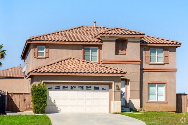 A beautiful Mediterranean-style home boasts elegant stucco walls, a tiled roof, and charming arches, creating a warm, inviting atmosphere with timeless architectural appeal.