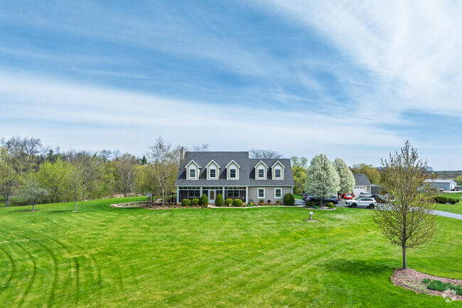 A picturesque modern farm home sits on an expansive lawn.