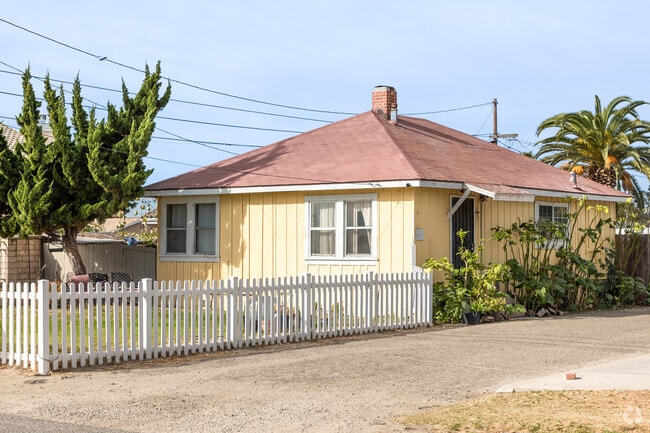 A cute yellow cottage has white picket fences in Nyeland Acres.