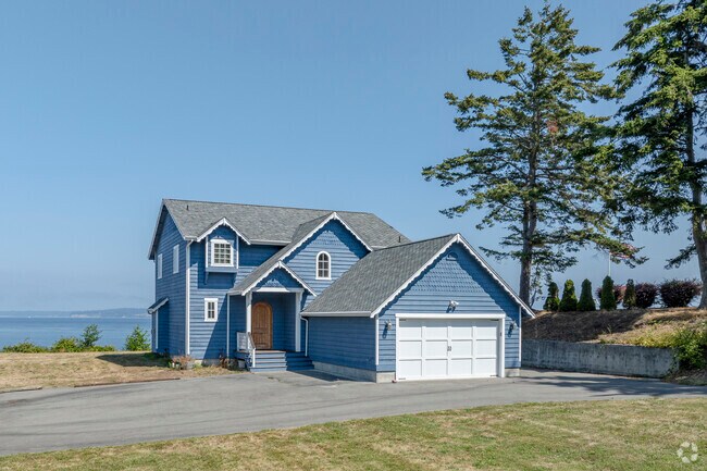 A traditional modern home sits on a wooded lot with water views in Hansville, WA.