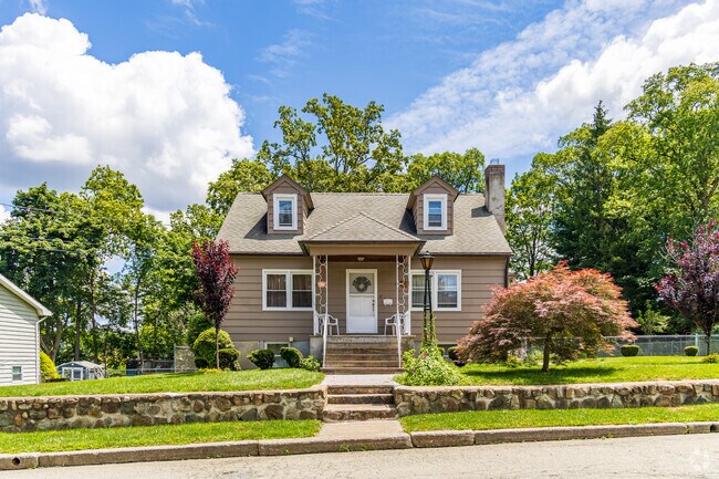 This cozy taupe cottage in Netcong delights with its tidy landscaping, classic dormers, and the kind of porch that feels made for morning coffee.