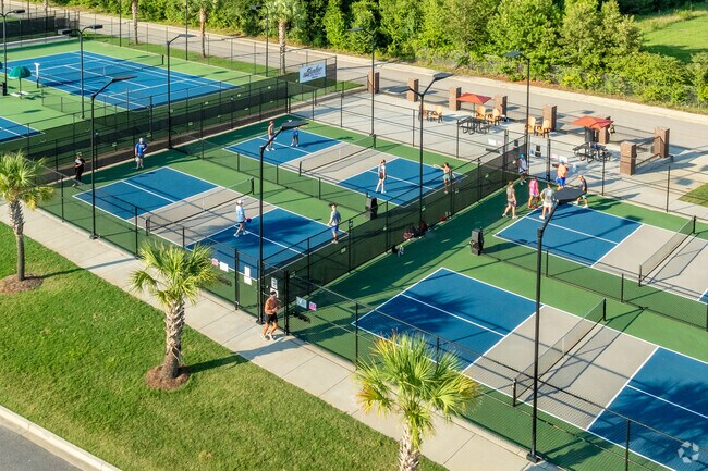 The Palmetto Park pickleball courts are illuminated and feature a patio-style seating area.