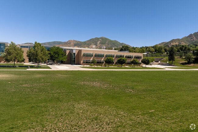 A tan brick building is sandwiched by green mountains and a green field at Hillside Middle Schoo