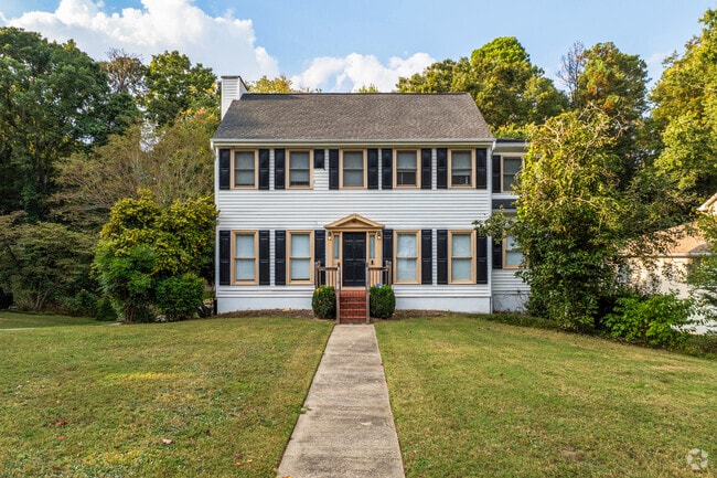 A white colonial revival style home in Bradford-Ridgewood has black shutters and yellow accents.